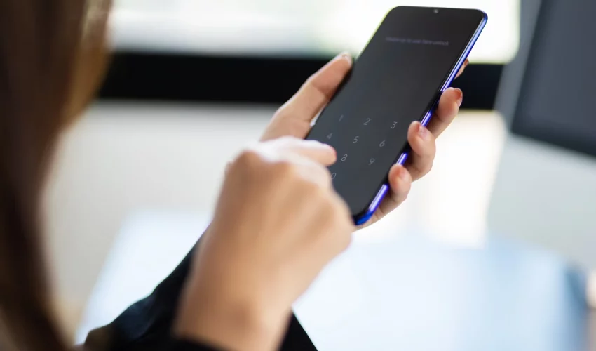 Mulher segura em sua mão um celular e faz o desbloqueio da tela