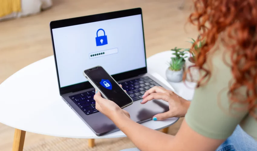 mulher faz verificação de dois fatores entre o celular e o computador para proteger suas contas