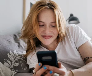 Mulher mexe feliz no celular depois das dicas para ter segurança de namoro online