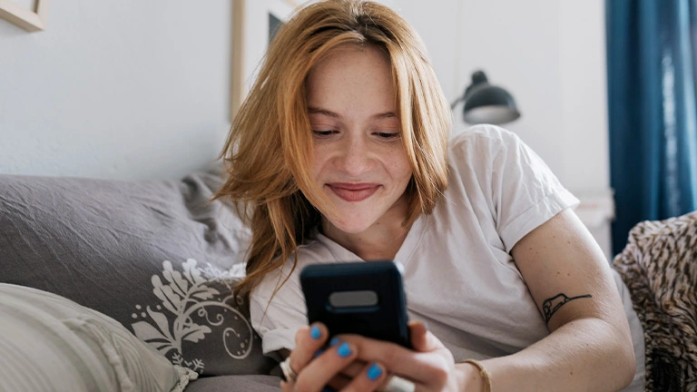Mulher mexe feliz no celular depois das dicas para ter segurança de namoro online