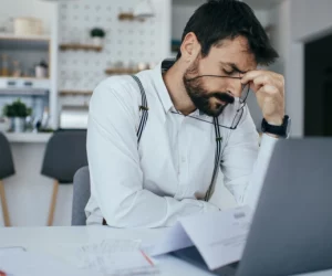 Homem sente cansaço diante do computador. Ele tenta entender os impactos do machismo e se desconstruir,