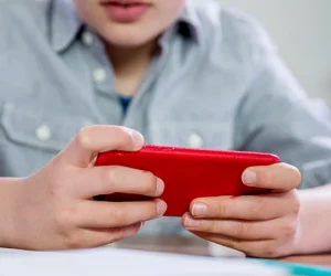 Menino segura celular durante a aula, o que faz com que muitos pais se questionem qual é a hora de dar celular para criança