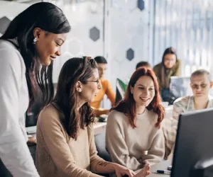 Mulheres da área de tecnologia discutem enquanto olham os seus computadores para concluírem os seus trabalhos