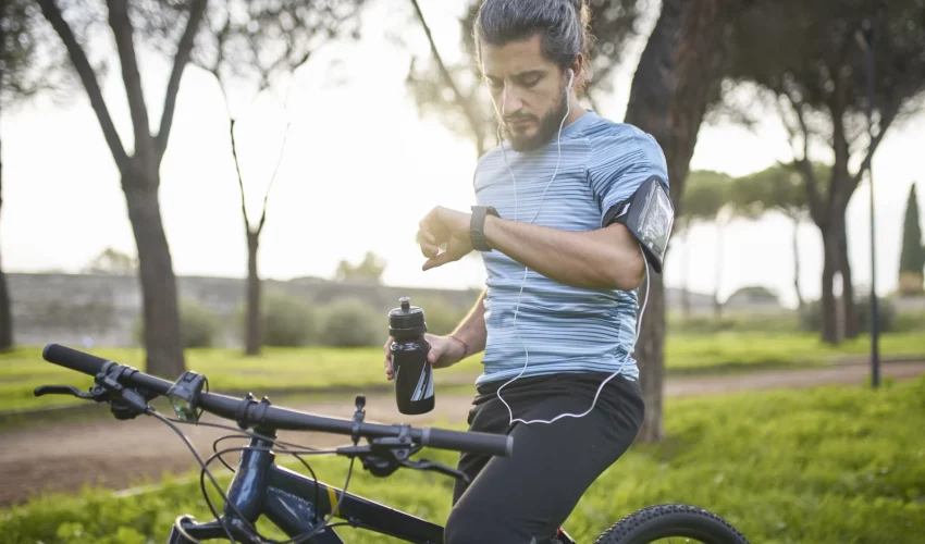 Homem checa seu desempenho na bicicleta no seu relógio para cuidar da sua saúde mental