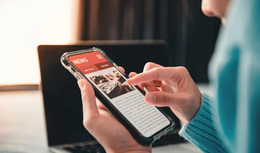 Pessoa aumenta a tela do celular para ler notícia, ainda não tendo certeza se é fake news ou não