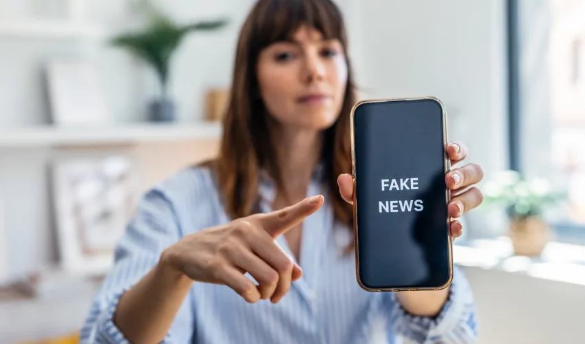 Mulher aponta para tela de celular escrito fake news