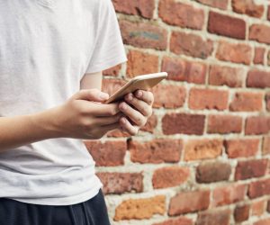 Jovem usa celular escondido. Os jovens têm propensão a aprenderem com a cultura incel, por isso, é importante guiá-los para uma educação mais inclusiva
