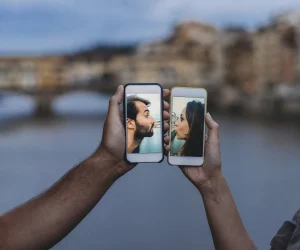 um celular do lado do outro se beijam através das câmeras dos celulares