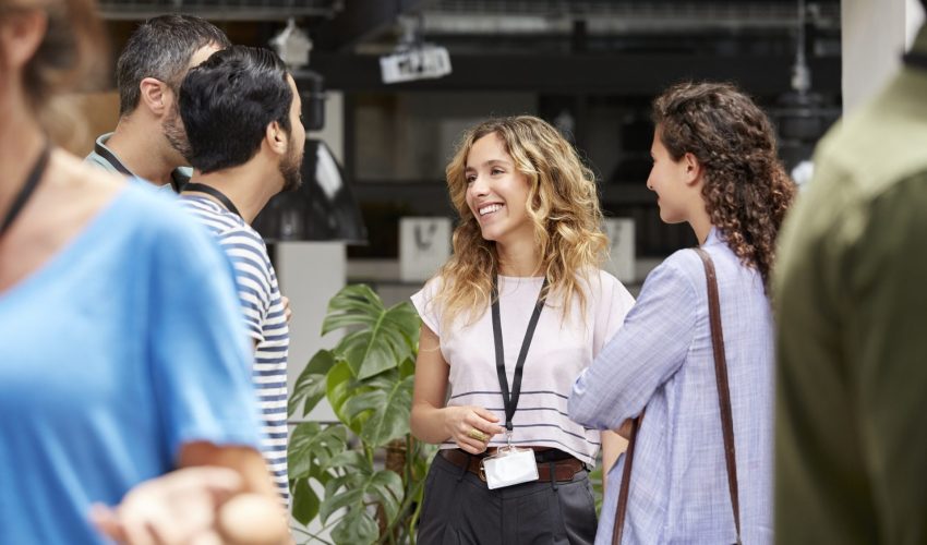 Mulher sorri enquanto faz networking em convenção de trabalho