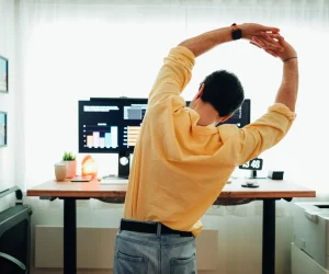 Homem faz alongamento na frente do seu local de trabalho para ter mais ergonomia na rotina