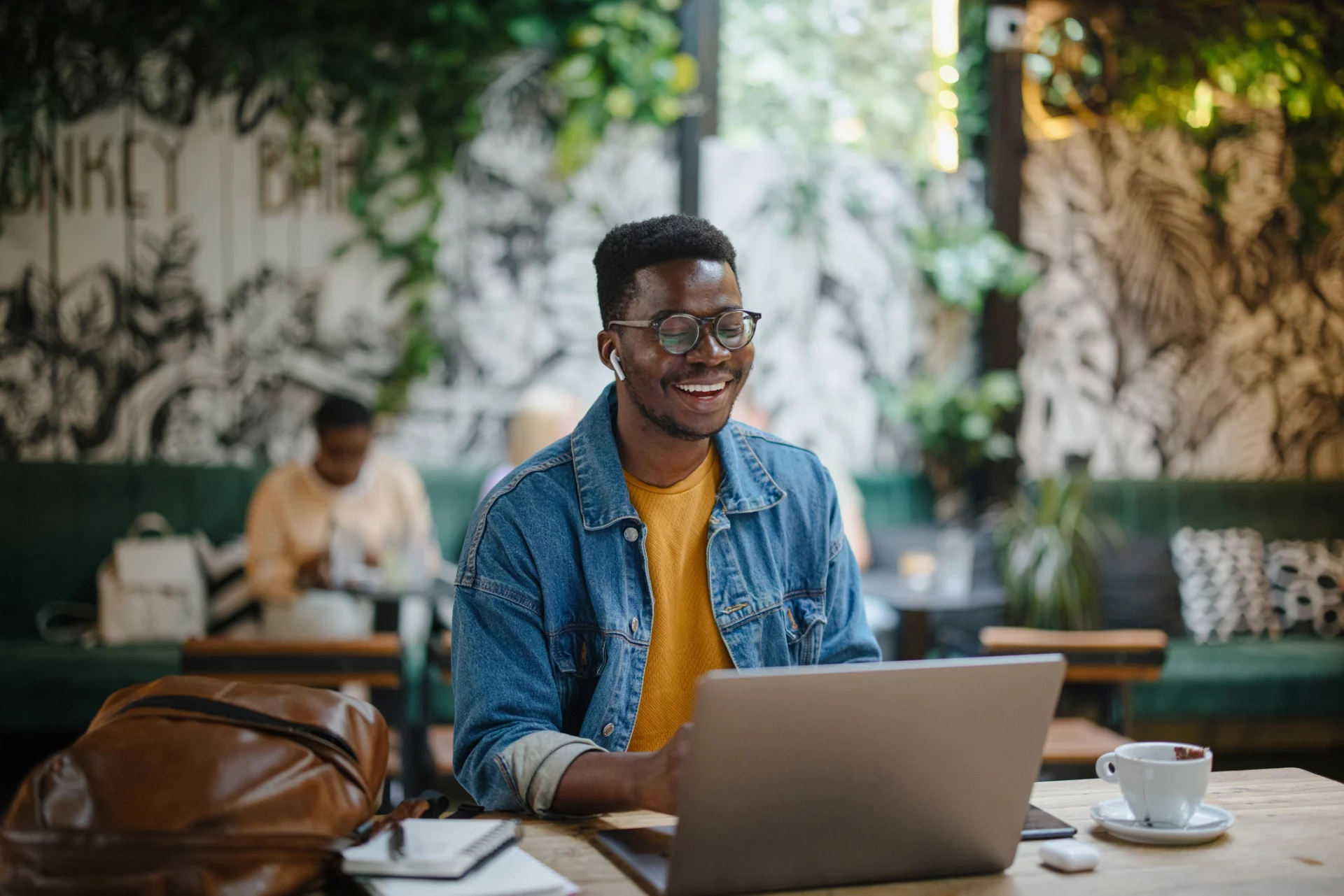 Homem negro sorri na frente do computador enquanto trabalha e estuda, sabendo que direitos foram conquistados por causa da cidadania digital