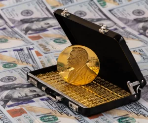 Uma réplica da medalha de ouro do Prêmio Nobel dentro de uma maleta pequena com barras de ouro, sobre um fundo de notas de dólares.
